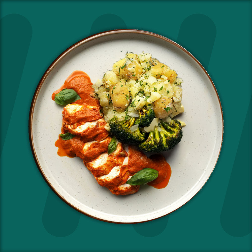 A colorful plate featuring shredded Mexican-spiced chicken garnished with fresh herbs, served alongside a portion of vibrant green cilantro rice. Complementing the dish is a side of roasted corn mixed with crumbled feta cheese, adding a touch of creaminess and texture. The meal is presented on a minimalist ceramic plate with a dark rim, set against a rich green background for a fresh and appetizing presentation. prepped meal.