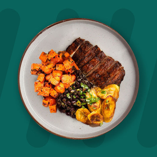  A colorful plate featuring shredded Mexican-spiced chicken garnished with fresh herbs, served alongside a portion of vibrant green cilantro rice. Complementing the dish is a side of roasted corn mixed with crumbled feta cheese, adding a touch of creaminess and texture. The meal is presented on a minimalist ceramic plate with a dark rim, set against a rich green background for a fresh and appetizing presentation. prepped meal.