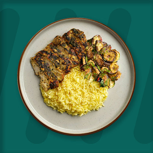  A colorful plate featuring shredded Mexican-spiced chicken garnished with fresh herbs, served alongside a portion of vibrant green cilantro rice. Complementing the dish is a side of roasted corn mixed with crumbled feta cheese, adding a touch of creaminess and texture. The meal is presented on a minimalist ceramic plate with a dark rim, set against a rich green background for a fresh and appetizing presentation. prepped meal.