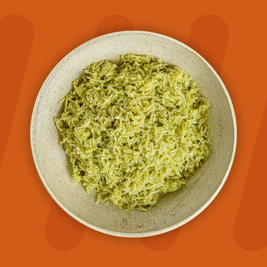 A bowl of vibrant green cauliflower rice, lightly seasoned, set against an orange background