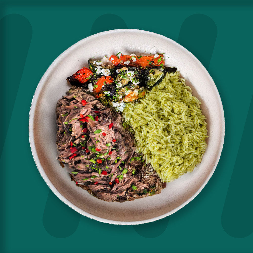  A colorful plate featuring shredded Mexican-spiced chicken garnished with fresh herbs, served alongside a portion of vibrant green cilantro rice. Complementing the dish is a side of roasted corn mixed with crumbled feta cheese, adding a touch of creaminess and texture. The meal is presented on a minimalist ceramic plate with a dark rim, set against a rich green background for a fresh and appetizing presentation. prepped meal.